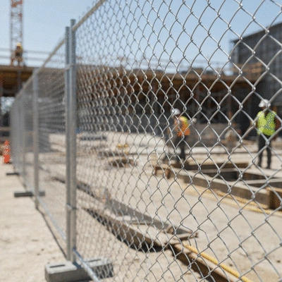 Temporary fence surrounding a construction site with workers in the background, no text, no words, no typography